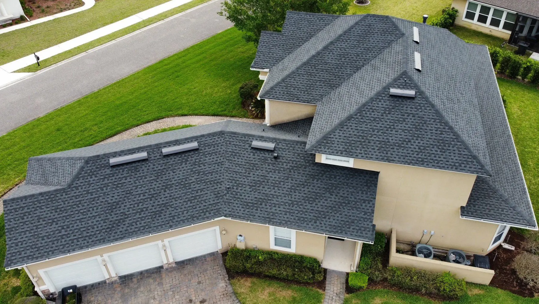 Aerial view of house with dark roof.