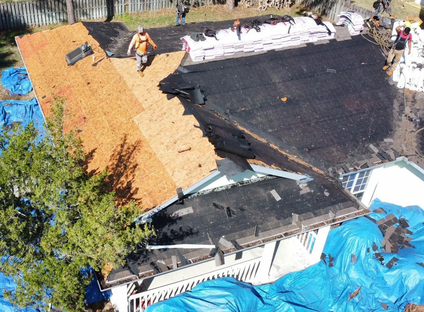 Roof repair with workers and tarps.