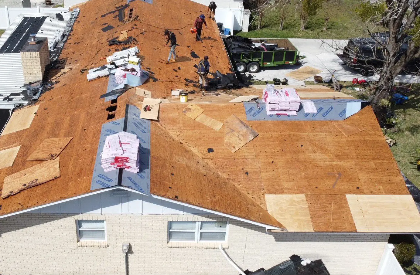Workers repairing roof with wooden panels.