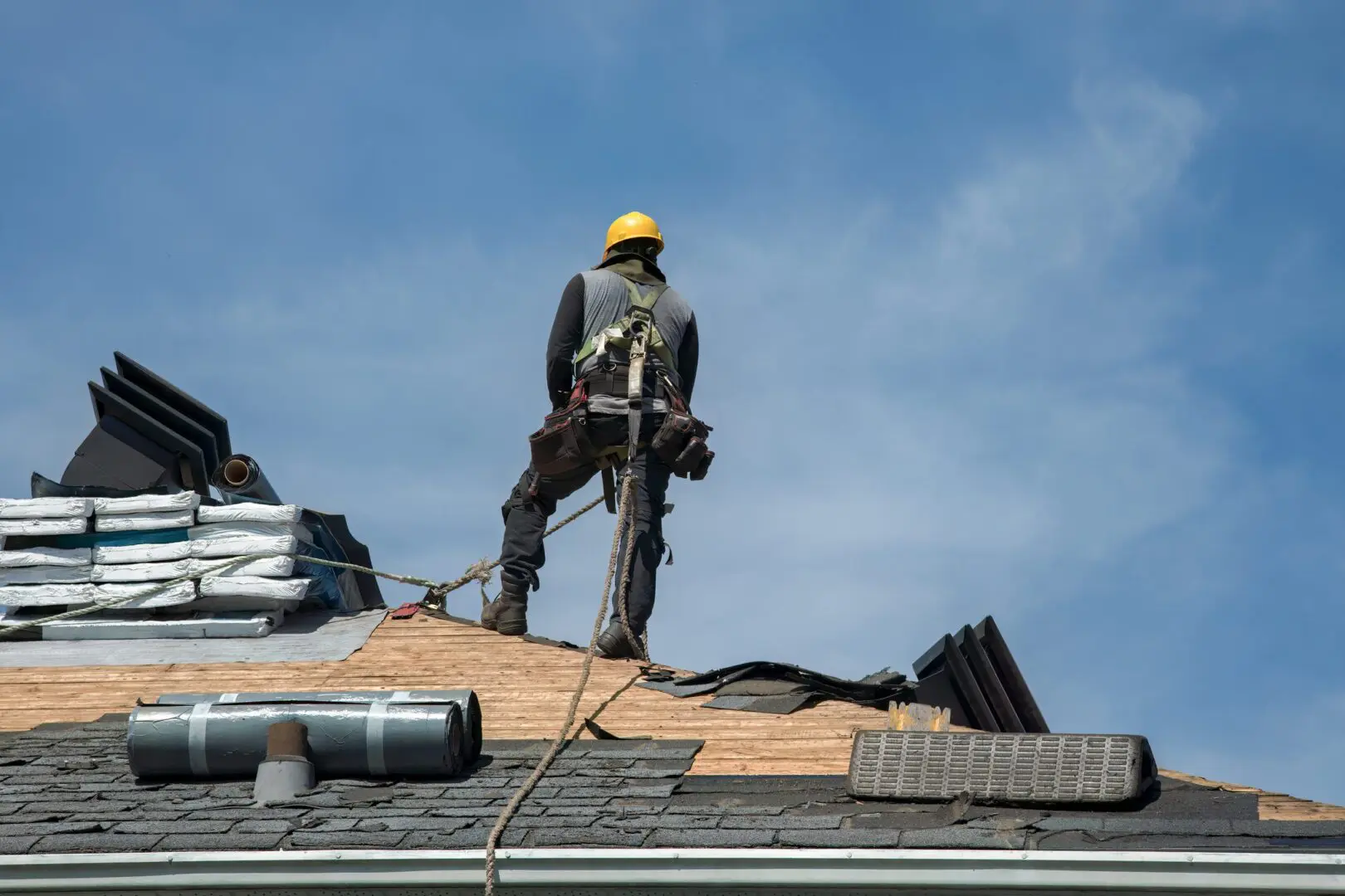Worker on roof wearing safety harness.