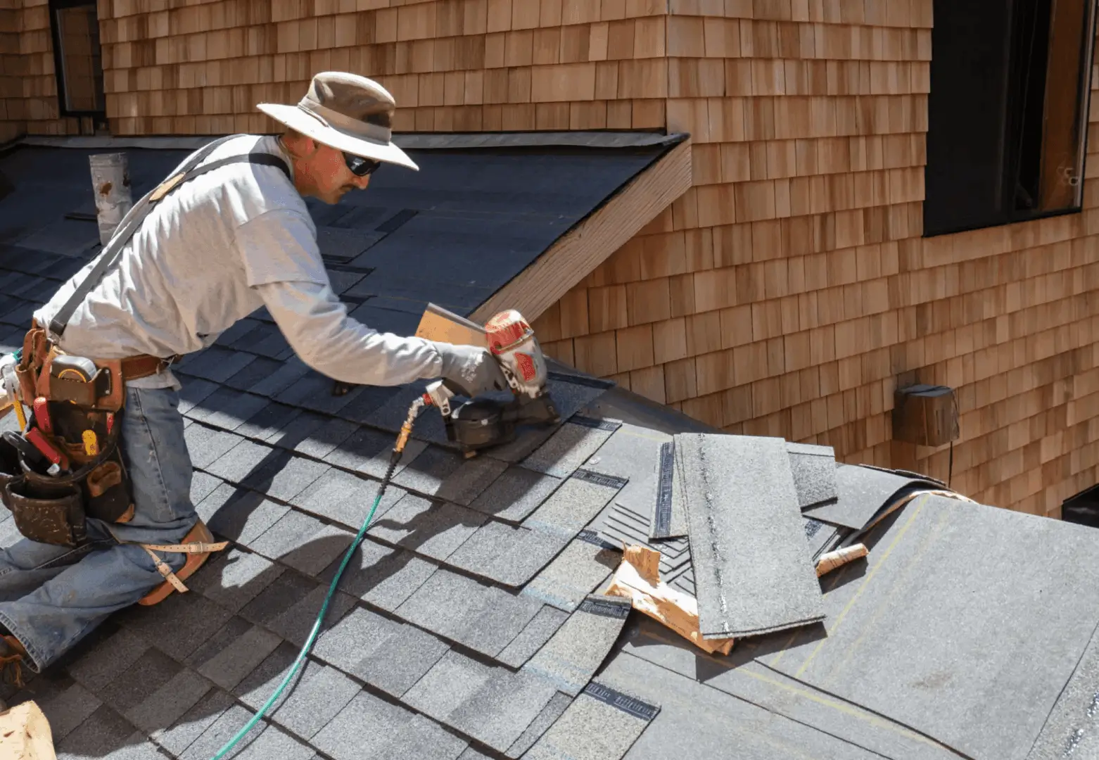 Worker installing asphalt shingles on a residential roof.